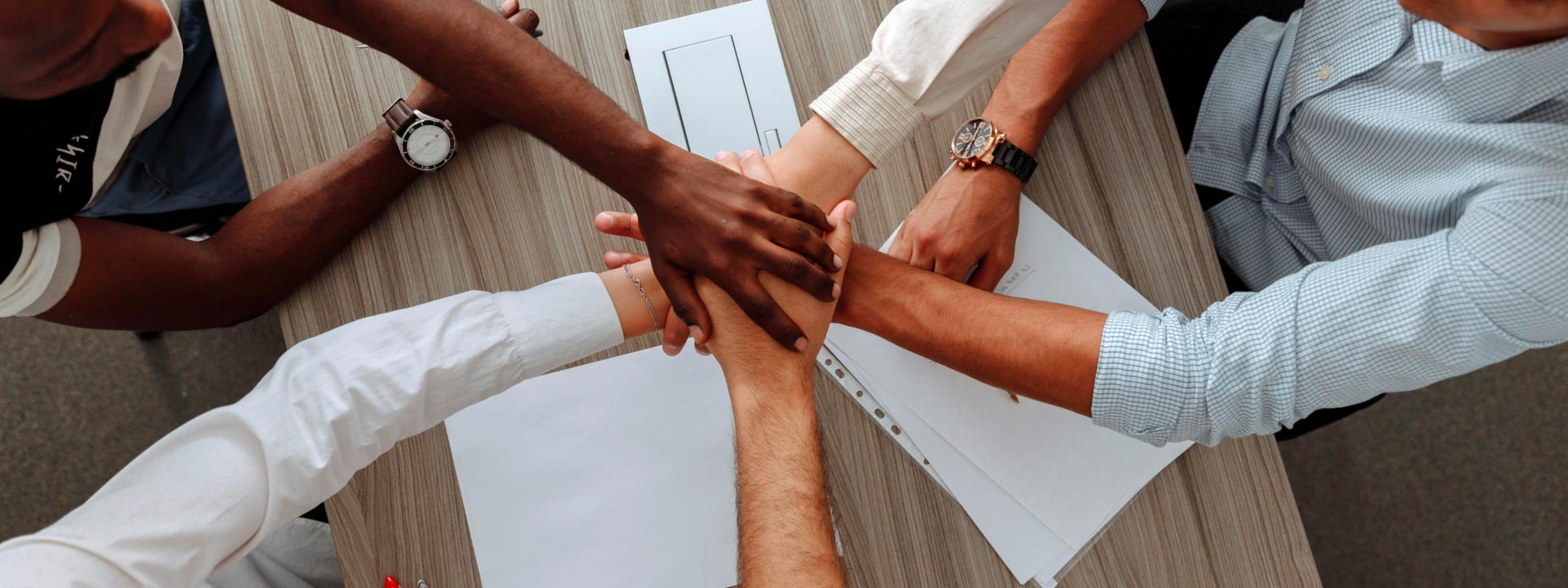 Diversas mãos unidas sobre uma mesa, simbolizando trabalho em equipe, unidade e colaboração, representando o compromisso da Solavita com parcerias sólidas e esforços de vendas cooperativas