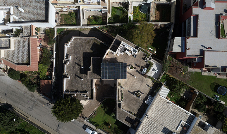 Vista de cima da instalação de painéis solares no telhado com o inversor híbrido da Solavita e a integração do conjunto de baterias, destacando soluções residenciais eficientes de energia renovável