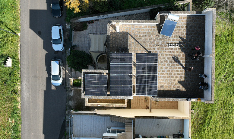 Vista de cima da instalação de painéis solares no telhado com o inversor híbrido da Solavita e a integração do conjunto de baterias, destacando soluções residenciais eficientes de energia renovável