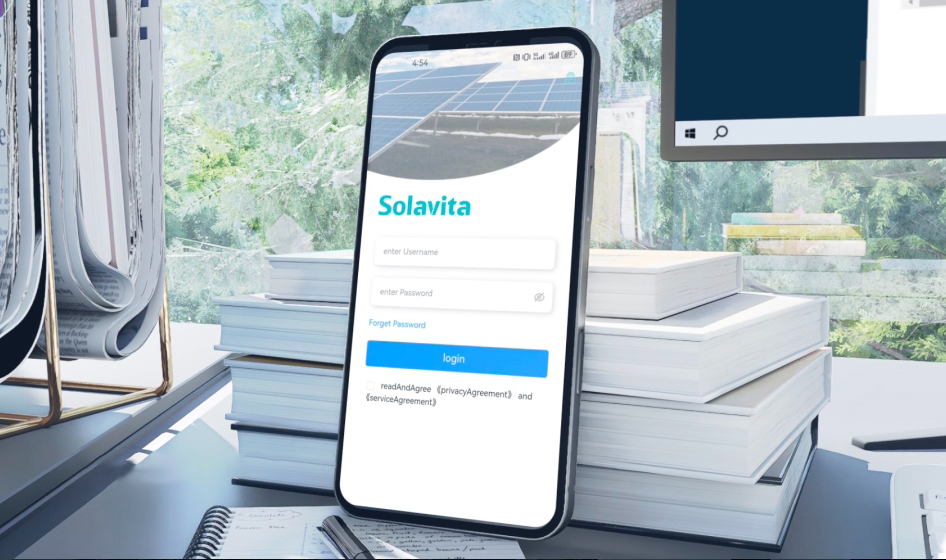 A plataforma de gerenciamento de energia Solavita Cloud exibida em uma tela grande, mostrando uma interface detalhada da lista de usinas com diversos dados das estações de energia solar, incluindo localização, capacidade e indicadores de status do sistema. Um smartphone com a tela de login da Solavita Cloud é visível em primeiro plano, destacando a acessibilidade da plataforma em diversos dispositivos. Localizado em um ambiente de trabalho moderno com vegetação visível na área externa